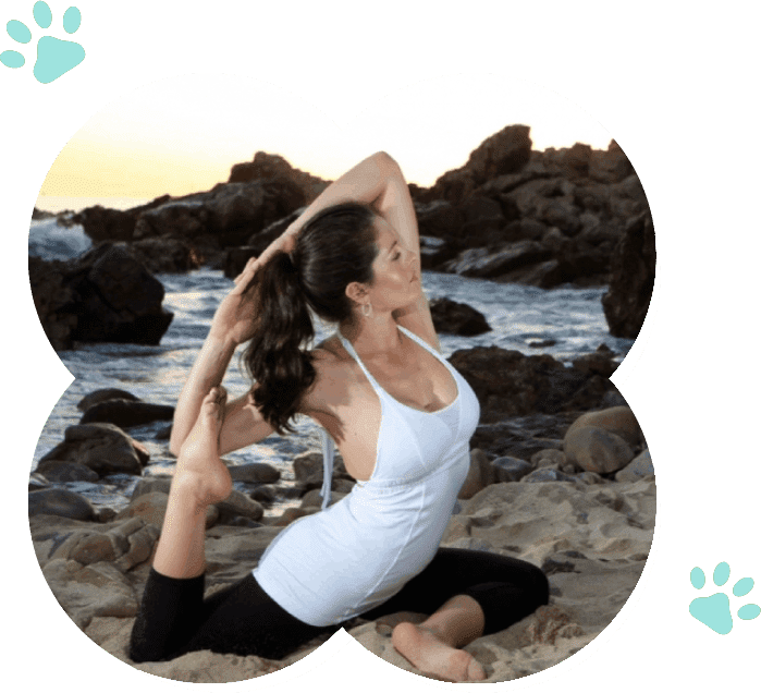 A woman strengthening her connection with her dog through doga sessions on the beach with dog paws.